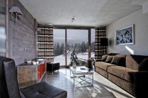 a living room with a couch and a large window at CGH Résidence Boutique Le Centaure in Flaine