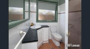 a bathroom with a toilet and a sink and a window at 6 Bedrooms/9 Beds Huge House|City+Park Views|Beach in Frankston
