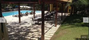 una piscina con mesas y sillas junto a un complejo en Vila Verona en Praia do Forte
