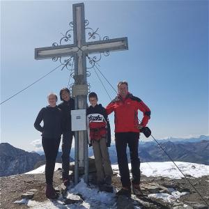 um grupo de pessoas ao lado de uma cruz numa montanha em Apartmenthaus Innerkratzerhof em Prägraten