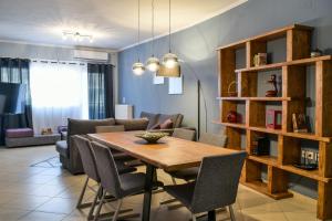 Meteora View Modern Apartments في كالامباكا: غرفة معيشة مع طاولة وكراسي خشبية