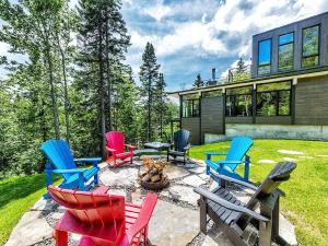 a group of colorful chairs sitting around a fire pit at Le Charlevoix - Résidences Boutique. in Petite-Rivière-Saint-François