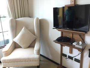een woonkamer met een witte stoel en een flatscreen-tv bij Venetian Signature PoolAccess Resort Jomtian Pattaya in Jomtien Beach