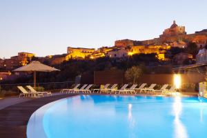 a swimming pool with chairs and a view of a city at Eolian Milazzo Hotel in Milazzo