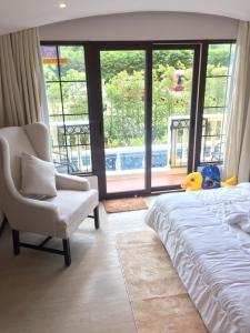 a bedroom with a bed and a chair and large windows at Venetian Signature PoolAccess Resort Jomtian Pattaya in Jomtien Beach