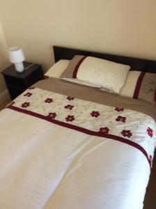 a bed with a blanket with red flowers on it at Wexford Town Opera Mews - 1 Bed Apartment in Wexford