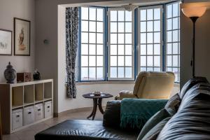 a living room with a couch and a chair and windows at Casa das Conchas in Ericeira