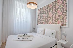リスボンにあるBmyGuest - Ambassador Boutique Apartment IIの花柄の壁紙を用いたベッドルーム1室(白い大型ベッド1台付)