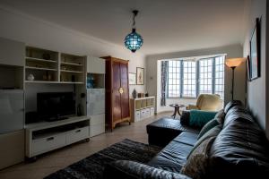 a living room with a couch and a television at Casa das Conchas in Ericeira