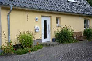 una casa amarilla con una puerta blanca y un banco en Ankerplatz Kiel, en Kiel