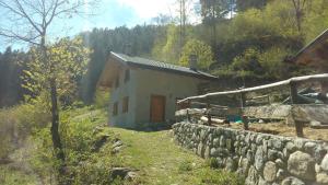 a small house with a stone wall next to a building at Chalet Immerso nel Verde in Strembo