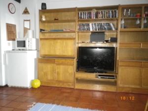 una sala de estar con un gran centro de entretenimiento con TV en Estudio T0 sobre a praia, en Sesimbra