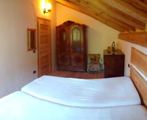 a bedroom with a white bed and a wooden cabinet at Chalet Immerso nel Verde in Strembo