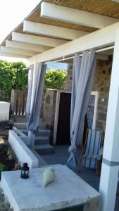 eine Terrasse mit weißen Vorhängen sowie einem Tisch und Stühlen in der Unterkunft Il Dammuso di Tanit in Pantelleria