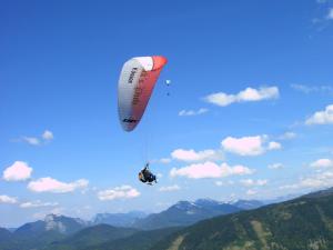 una persona colgando de un paracaídas en el cielo en Gästehaus Grünbacher en Kössen