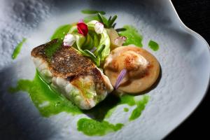 a plate of food with a piece of fish and vegetables at Occidental Faro in Faro