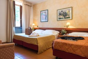 a hotel room with two beds and a chair at Hotel Delle Terme Santa Agnese in Bagno di Romagna