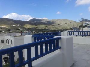 une balustrade bleue sur un balcon avec des montagnes en arrière-plan dans l'établissement Elichryson Studios, à Aegiali