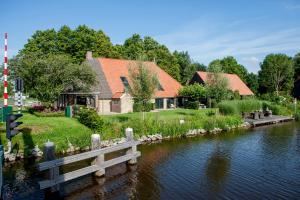 una casa junto a un río con un puente de madera en Uitgerust voor Zaken, en Heerenveen