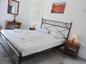 - une chambre dotée d'un lit avec des draps blancs dans l'établissement Elichryson Studios, à Aegiali