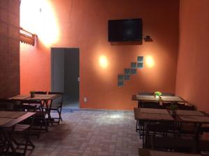a dining room with tables and a tv on the wall at Pousada Pai Nosso in Aparecida