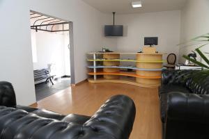 a living room with a leather couch and a tv at Hotel dos Lagos in Alfenas