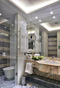 ein Badezimmer mit einem großen Spiegel, einer Badewanne und einem Waschbecken in der Unterkunft Hotel Savoy Prague in Prag