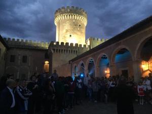 una multitud de personas de pie en frente de un castillo en Antica Corte del Castello, en Fiano Romano