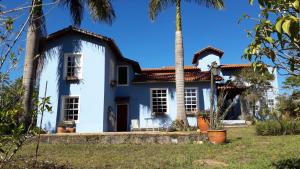 una casa bianca con una palma di fronte di Pousada Cantagalo Bichinho MG a Bichinho