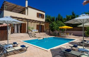 basen z leżakami i parasolami obok domu w obiekcie Amazing Villas in Crete w mieście Astérion