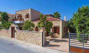 a house with a stone wall and a fence at Amazing Villas in Crete in Astérion