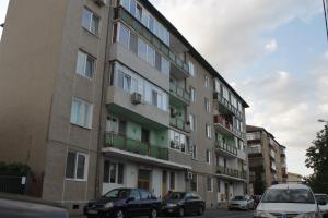 a tall building with cars parked in front of it at Joy Apartment in Timişoara