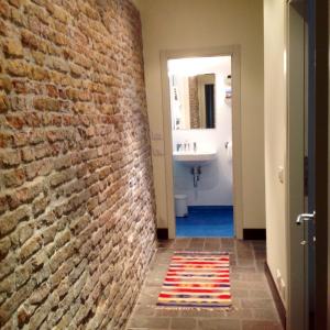 a hallway with a brick wall and a bathroom with a sink at Casa Poli in Ravenna