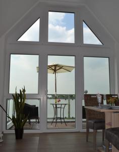- un salon avec de grandes fenêtres et une table avec un parasol dans l'établissement Steuerbord, à Horumersiel