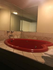 Red Carpet Inn في هوت سبرنغز: حوض استحمام أحمر في حمام مع مرآة