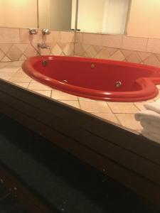 a red bath tub on a tiled floor in a bathroom at Red Carpet Inn in Hot Springs