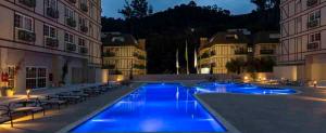 a pool with blue lights in a building at night at Flat Mangabeiras e manacás Granja Brasil Itaipava in Itaipava