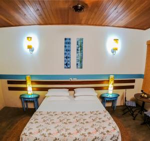 a bedroom with a bed with two tables and two lamps at Pousada Nascentes da Fortaleza, antiga Água Azul in São Sebastião do Paraíso