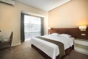 a bedroom with a large bed and a large window at Grand Kecubung Hotel in Pangkalan Bun