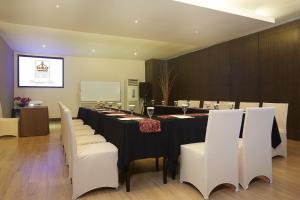 a conference room with a long table and white chairs at Grand Kecubung Hotel in Pangkalan Bun