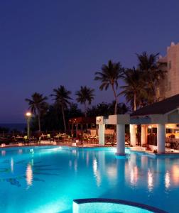 a large swimming pool at night with palm trees at Grand Hyatt Muscat in Muscat