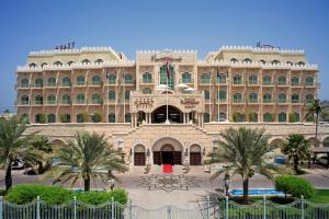 Un gran edificio con palmeras delante. en Grand Hyatt Muscat, en Mascate