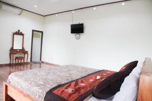 sypialnia z łóżkiem i telewizorem na ścianie w obiekcie Canang Sari House w mieście Ubud