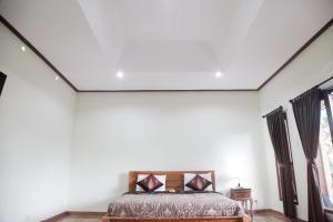 sypialnia z łóżkiem z białymi ścianami i oknami w obiekcie Canang Sari House w mieście Ubud
