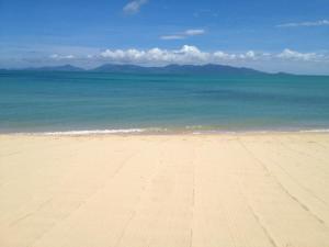 a sandy beach with the ocean and mountains in the background at The Cosy Maenam Beach Resort in Mae Nam