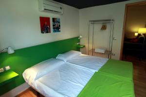 a green and white bed in a bedroom at Alojamiento ciudad las artes in Valencia