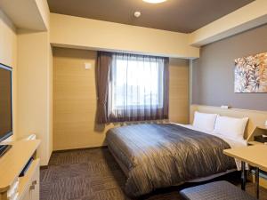 a hotel room with a bed and a window at Hotel Route Inn Minami Yokkaichi in Yokkaichi