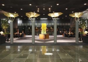a lobby with tables and people sitting in chairs at Hotel Granvia Kyoto in Kyoto