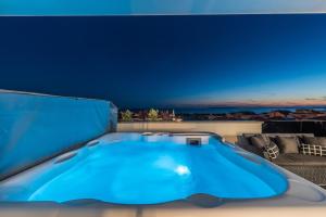 una vasca idromassaggio blu su un balcone con divano di Villa Magnifica Penthouse with Jacuzzi a Novalja (Novaglia)