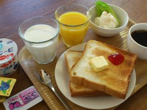 un plato de tostadas con mantequilla y dos vasos de leche en Atto Business Hotel Ichinoseki en Ichinoseki